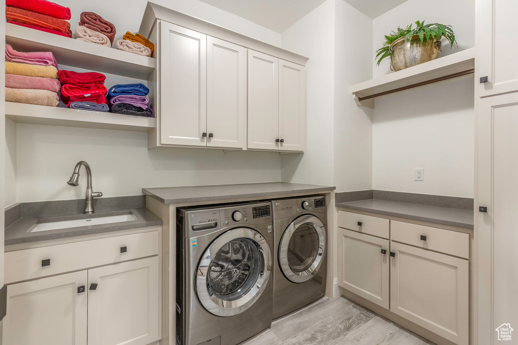 Laundry room with washer and dryer, cabinet space, and light wood finished floors