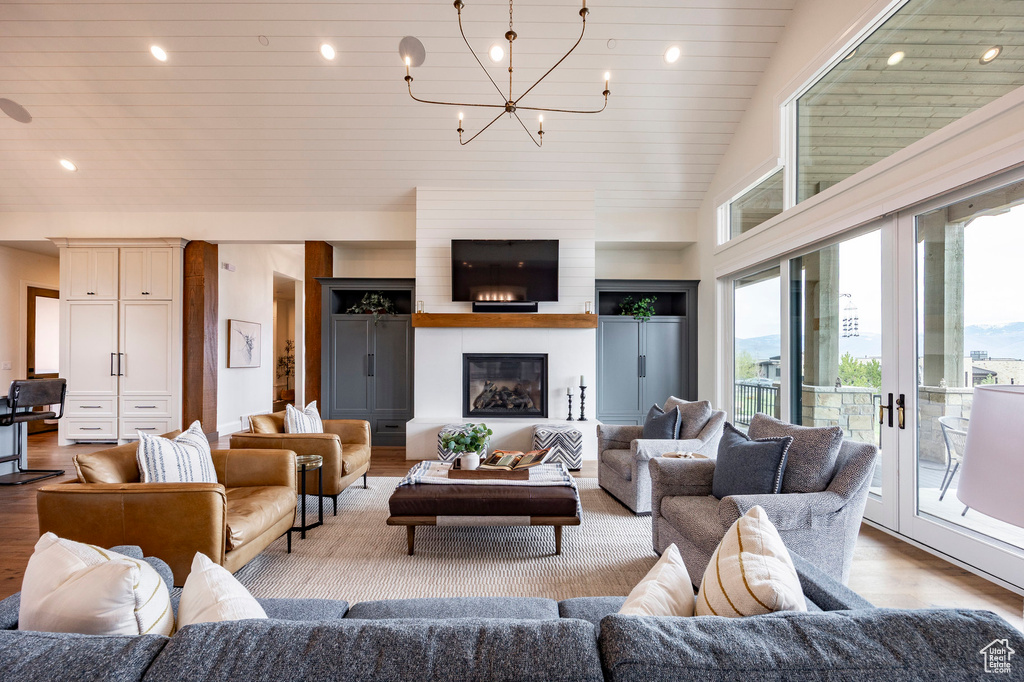 Living area featuring a chandelier, wood finished floors, wooden ceiling, a glass covered fireplace, and recessed lighting