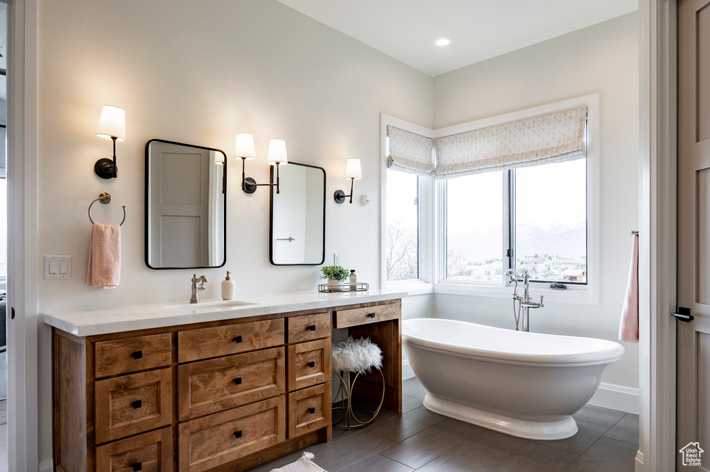 Bathroom with vanity, a soaking tub, and recessed lighting