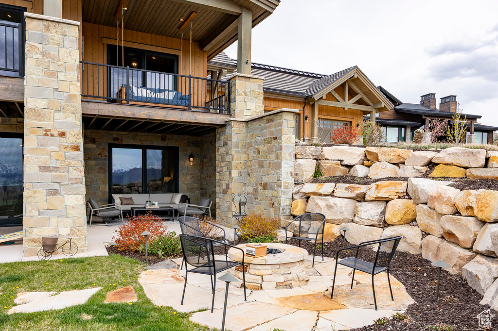 View of patio / terrace with a balcony and an outdoor living space with a fire pit