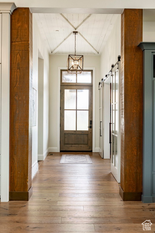 Entryway featuring a barn door, wood-type flooring, and beamed ceiling