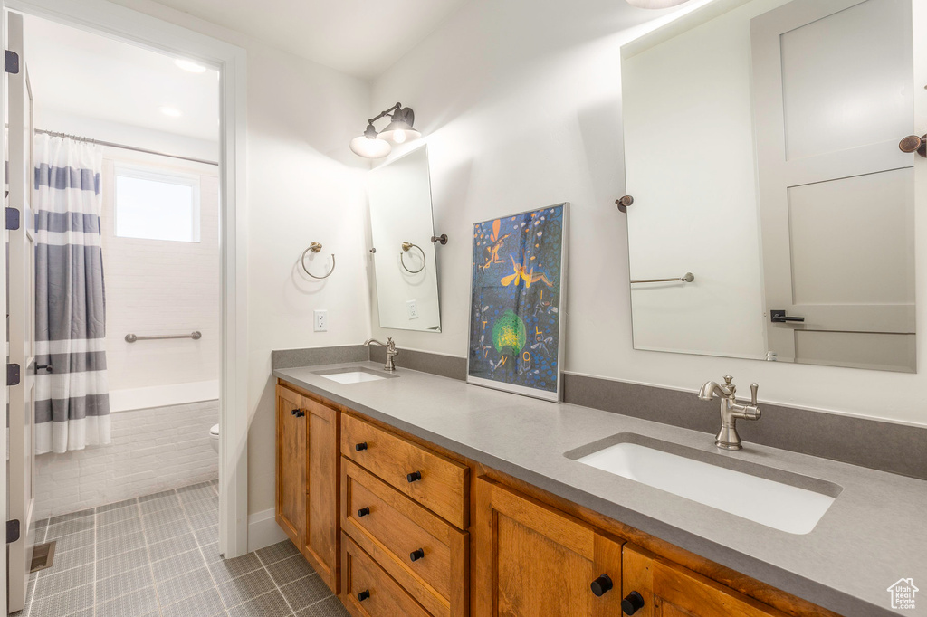 Bathroom with double vanity, tile patterned floors, toilet, and shower / tub combo with curtain