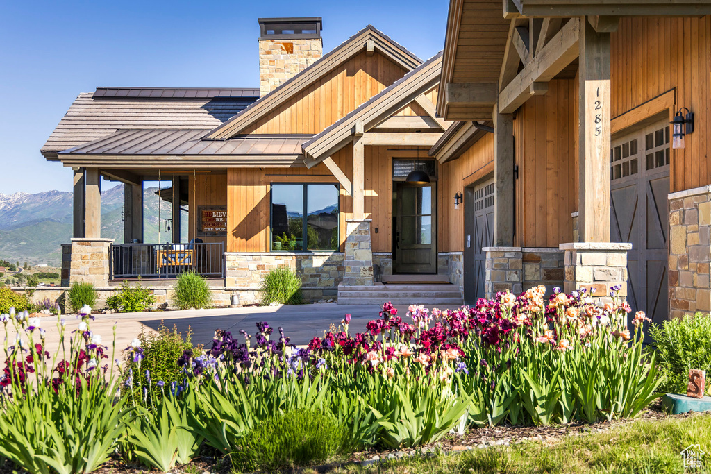 Entrance to property with a standing seam roof, a chimney, metal roof, stone siding, and a mountain view