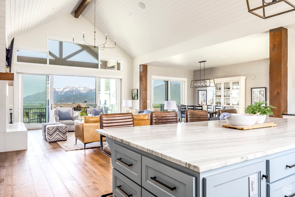 Kitchen with gray cabinetry, beamed ceiling, open floor plan, a mountain view, and light wood-style floors