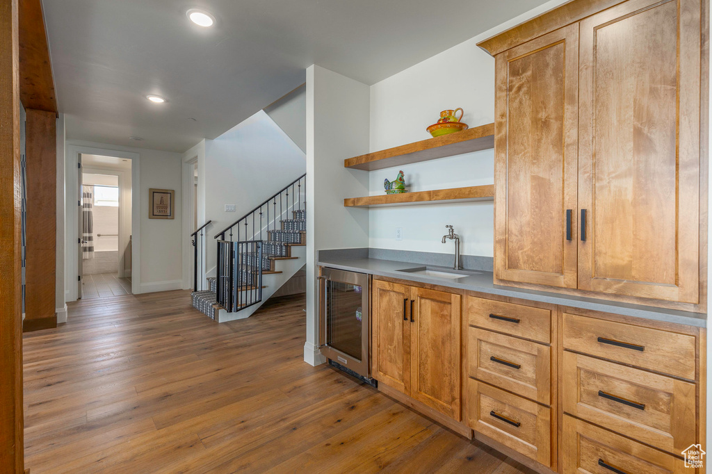 Indoor wet bar with beverage cooler, hardwood / wood-style floors, stairway, recessed lighting, and baseboards