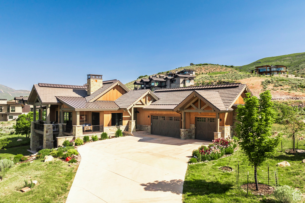 View of front facade featuring a chimney, stone siding, a garage, and a mountain view