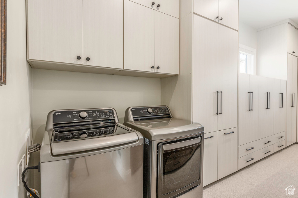 Washroom featuring cabinet space and washer and dryer