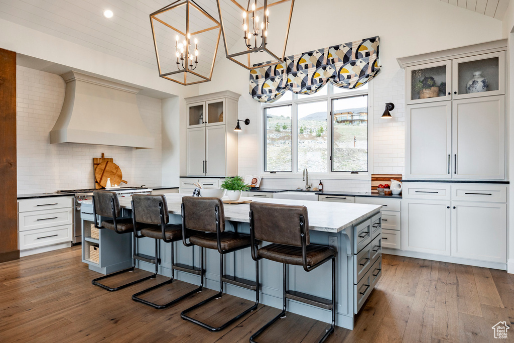Kitchen with custom range hood, tasteful backsplash, a kitchen island, a kitchen breakfast bar, and recessed lighting
