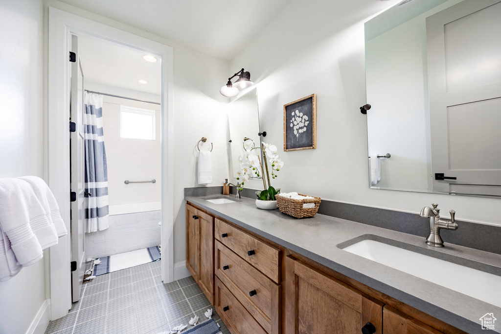 Full bathroom with double vanity, baseboards, and tile patterned flooring