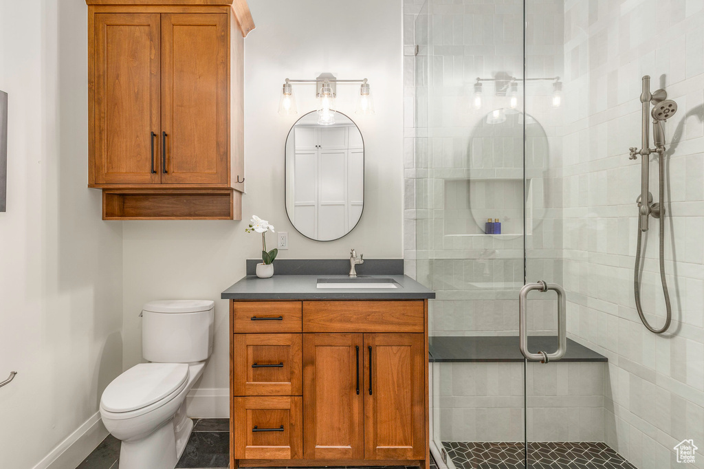 Bathroom with vanity, a shower stall, toilet, and baseboards
