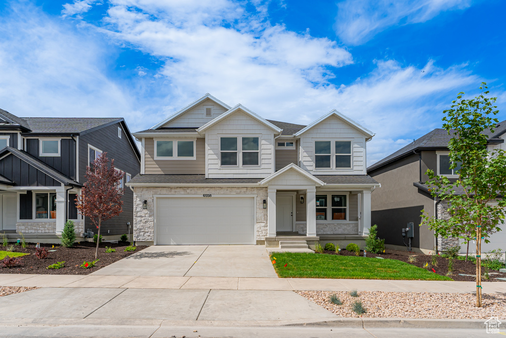 Craftsman-style house with driveway, an attached garage, and stone siding