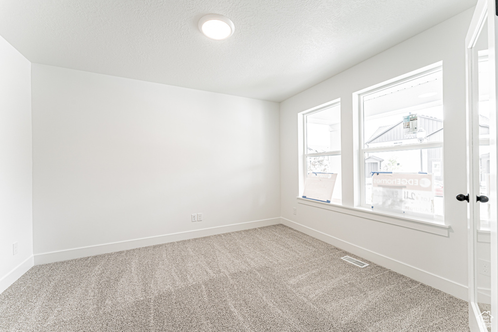 Unfurnished room with carpet floors and a textured ceiling