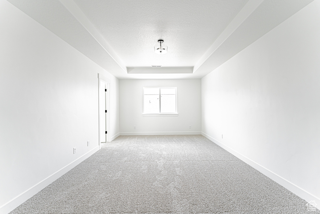 Carpeted empty room with a tray ceiling and a textured ceiling