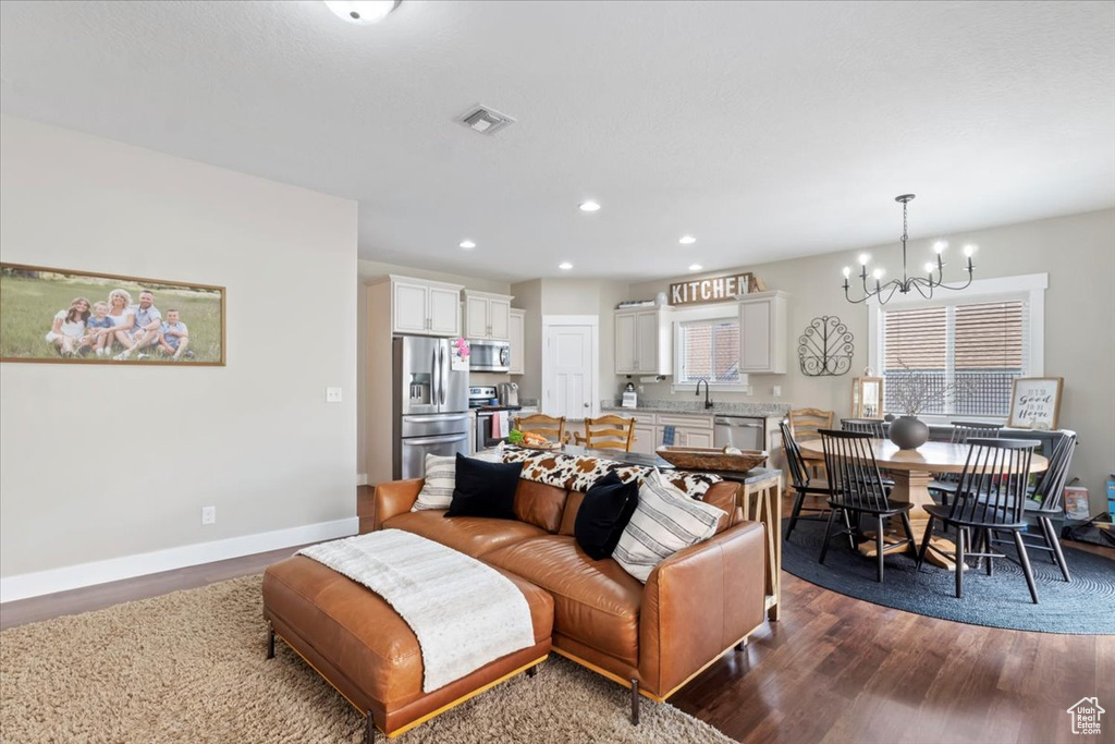 Living area featuring visible vents, baseboards, a notable chandelier, dark wood-style flooring, and recessed lighting