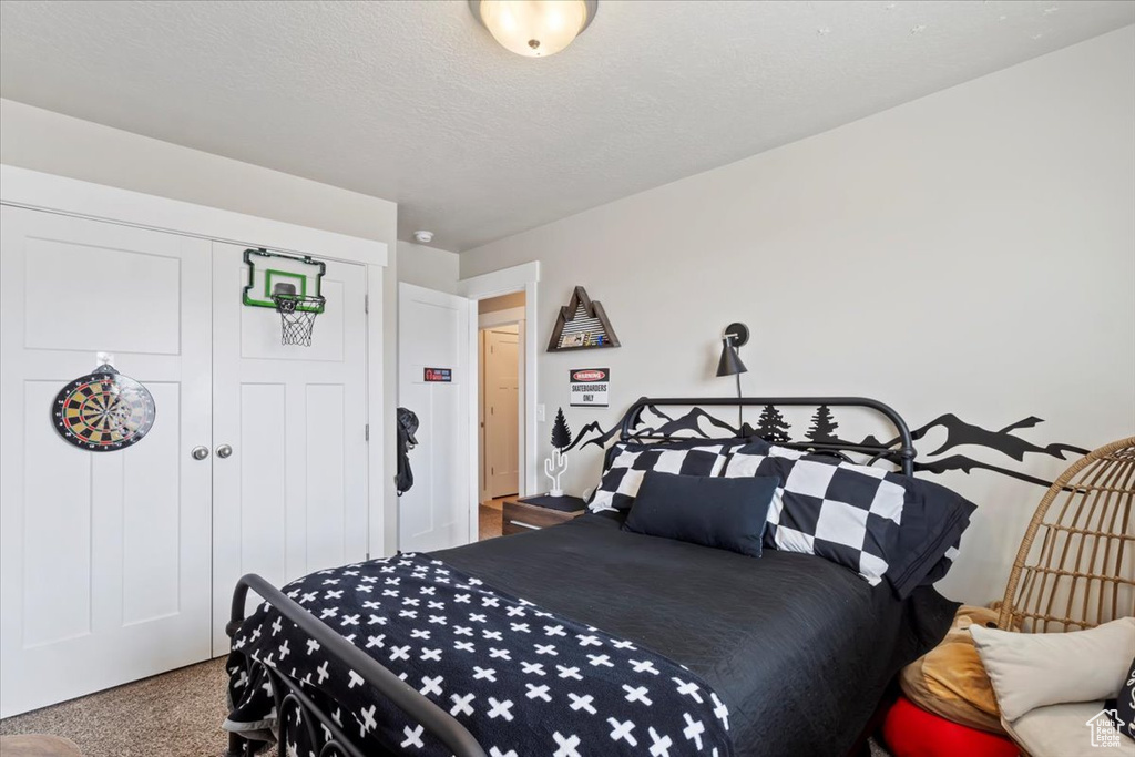Carpeted bedroom with a closet and a textured ceiling