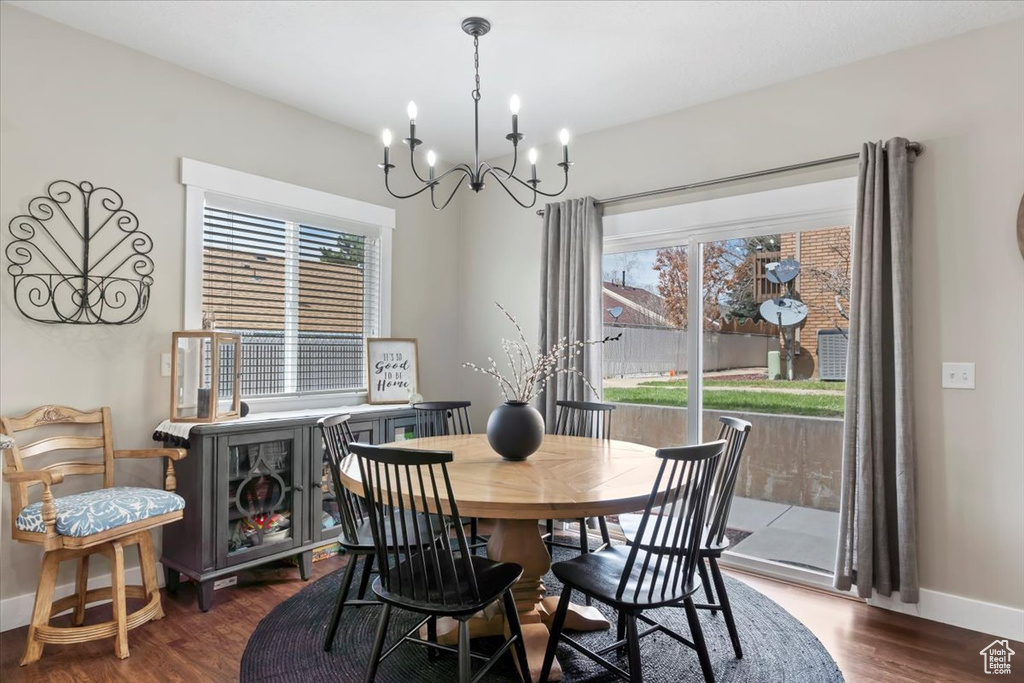 Dining room with dark wood-style floors, baseboards, an inviting chandelier, and a healthy amount of sunlight