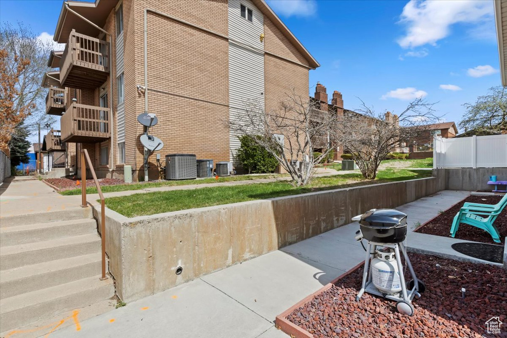Exterior space with central air condition unit, a balcony, fence, and brick siding