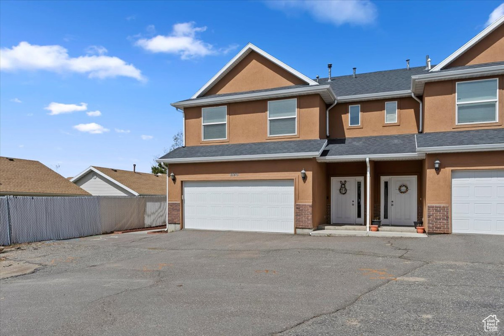View of front of house with driveway, a garage, stucco siding, and fence