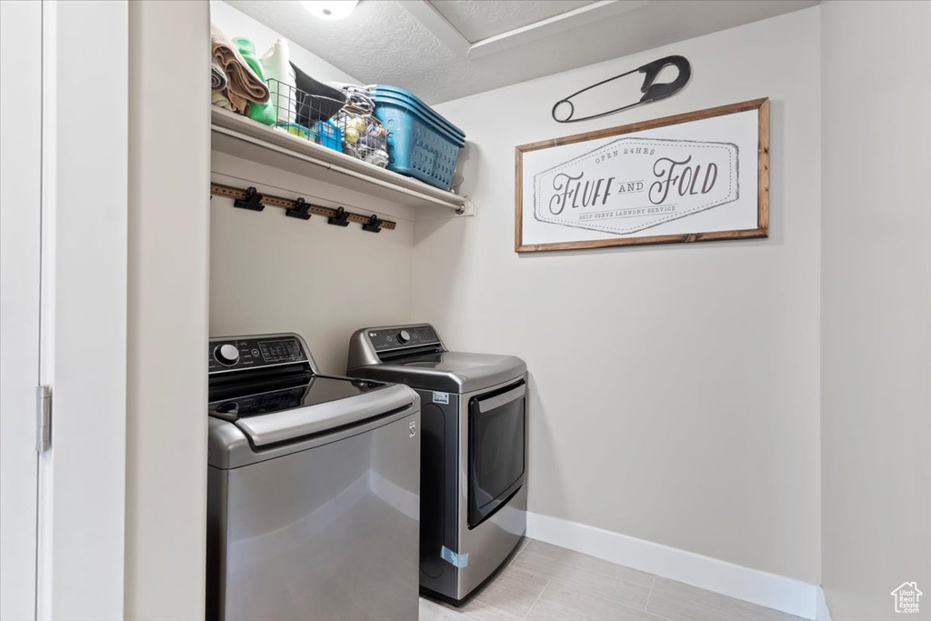 Laundry room with separate washer and dryer, laundry area, and baseboards