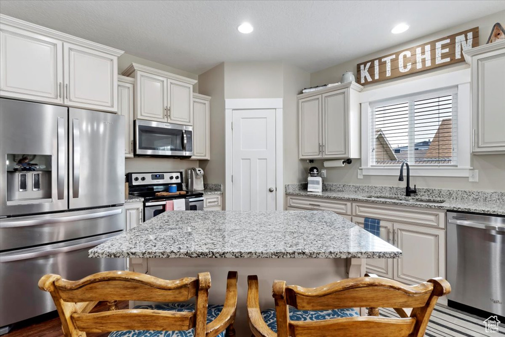 Kitchen with a center island, a sink, a kitchen bar, and appliances with stainless steel finishes
