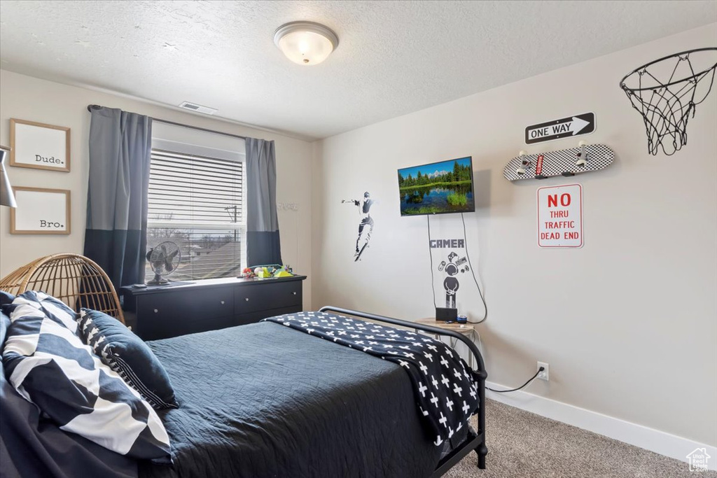Bedroom with carpet flooring, visible vents, a textured ceiling, and baseboards