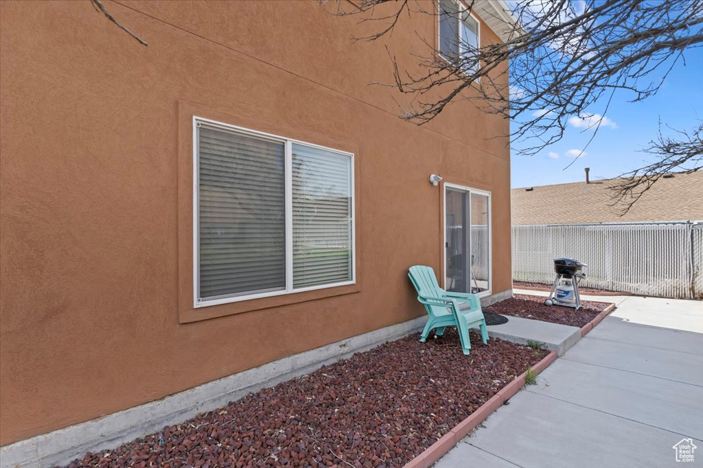 View of side of home with fence, a patio, and stucco siding