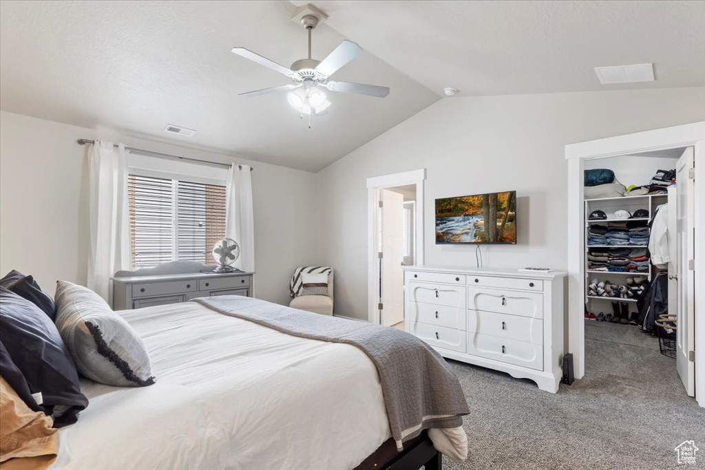 Bedroom with a closet, carpet flooring, a walk in closet, visible vents, and lofted ceiling