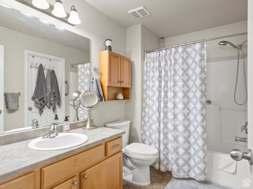 Bathroom featuring toilet, curtained shower, vanity, and visible vents