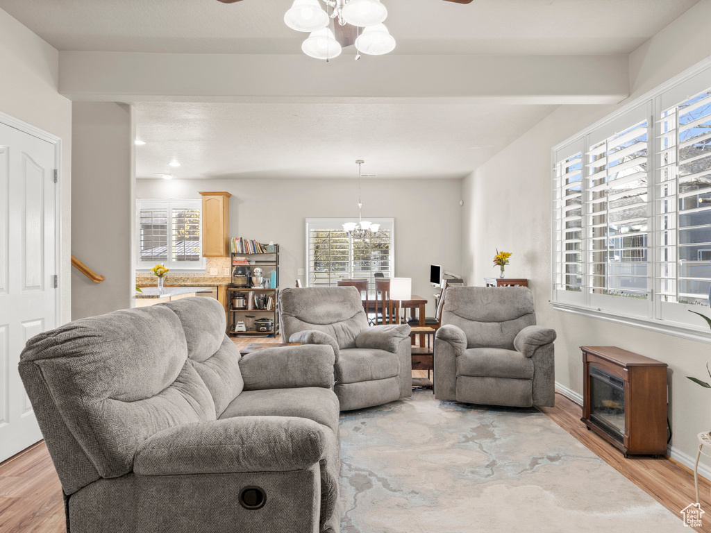 Living area with baseboards, light wood-style floors, and ceiling fan with notable chandelier
