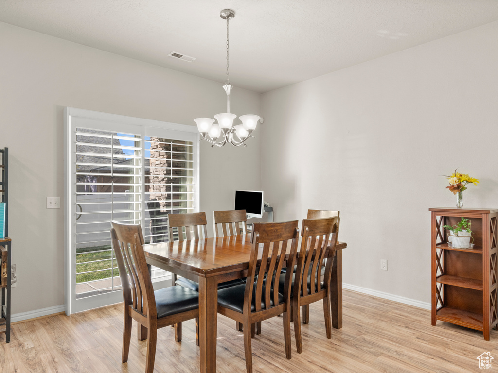 Dining area featuring a chandelier, light wood-style floors, visible vents, and baseboards