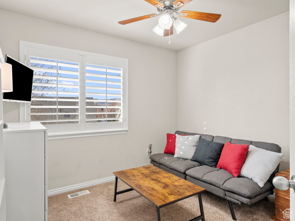 Carpeted living room featuring visible vents, baseboards, and a ceiling fan