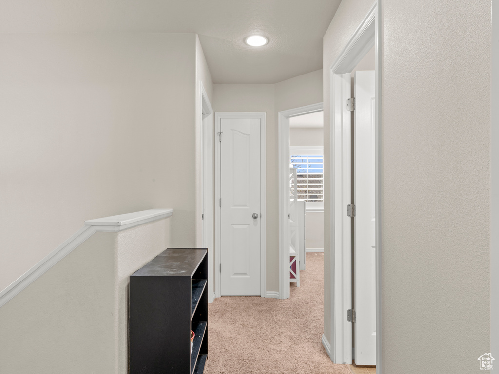 Hallway featuring light colored carpet and baseboards