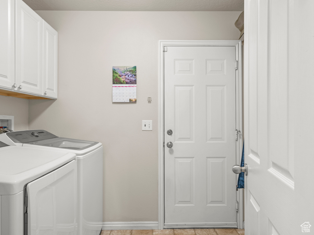 Washroom featuring cabinet space, washer and clothes dryer, and baseboards