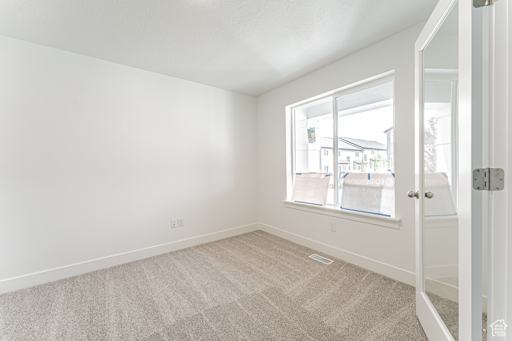 Carpeted empty room featuring baseboards and a textured ceiling