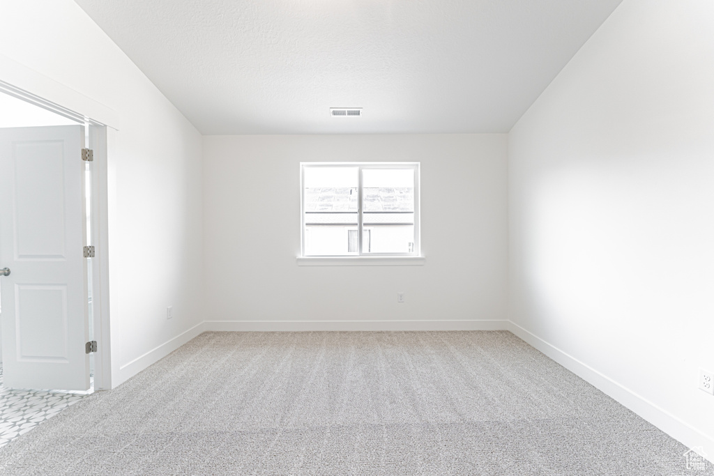 Spare room featuring light carpet and baseboards