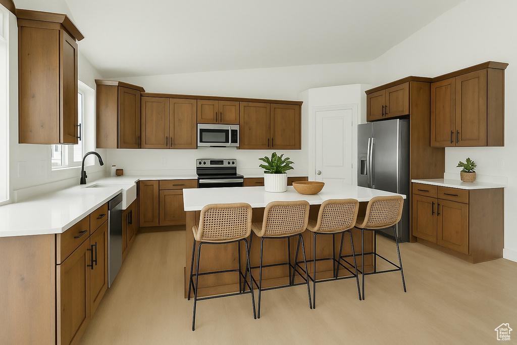 Kitchen featuring a kitchen breakfast bar, a kitchen island, a sink, lofted ceiling, and stainless steel appliances