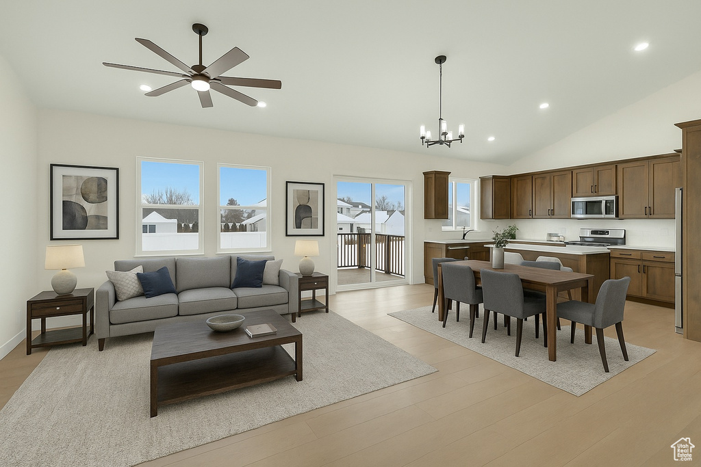 Living room featuring recessed lighting, light wood-style floors, ceiling fan with notable chandelier, and lofted ceiling