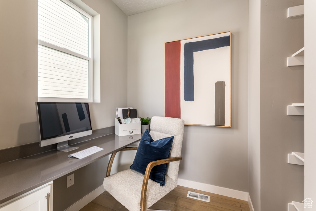 Office area with visible vents, baseboards, and wood finished floors