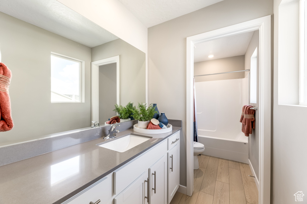 Full bathroom with tub / shower combination, vanity, toilet, and wood finished floors