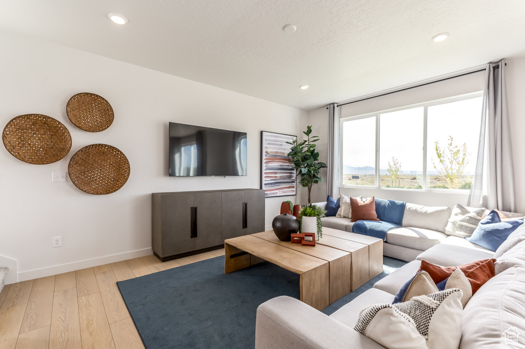 Living room featuring recessed lighting, light wood finished floors, baseboards, and a textured ceiling
