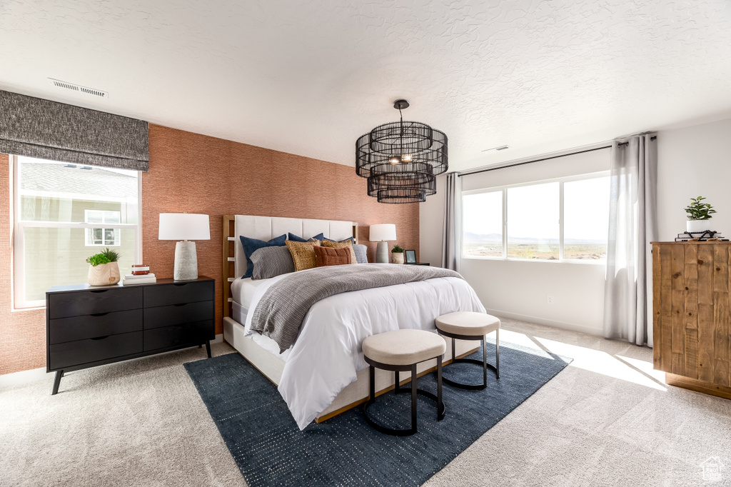 Bedroom with baseboards, a chandelier, a textured ceiling, visible vents, and light colored carpet