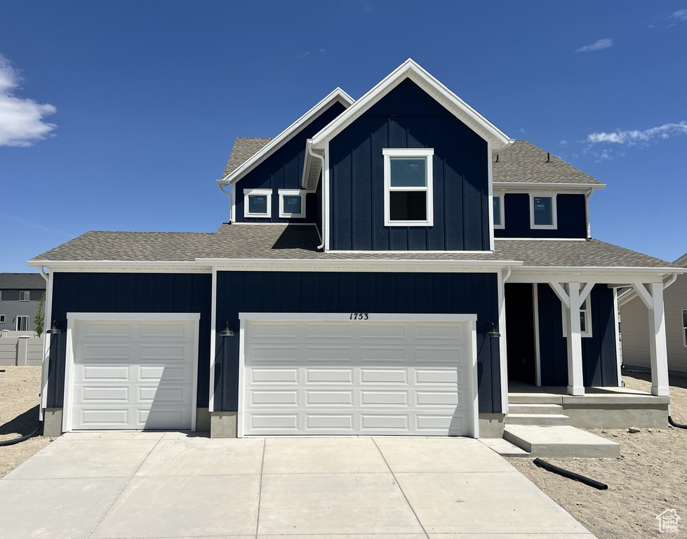 View of front of property with driveway, board and batten siding, a porch, and roof with shingles