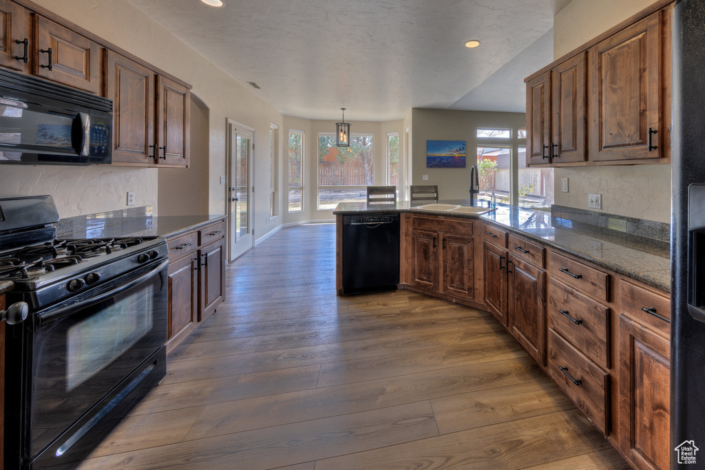 Kitchen featuring a peninsula, black appliances, recessed lighting, a sink, and dark wood-style floors