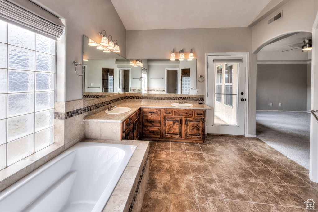 Bathroom featuring visible vents, a sink, tiled bath, and ceiling fan