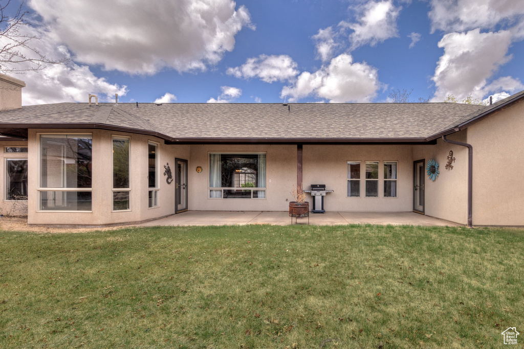 Rear view of property with a shingled roof, a yard, a patio area, and stucco siding