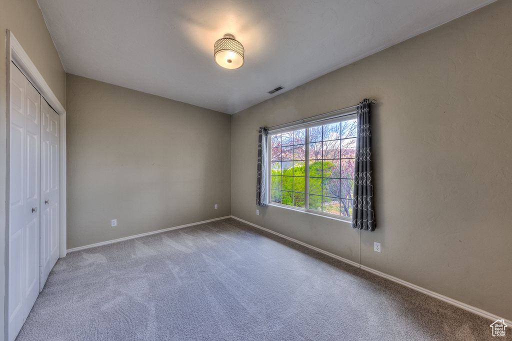 Unfurnished bedroom featuring a closet, carpet flooring, baseboards, and visible vents