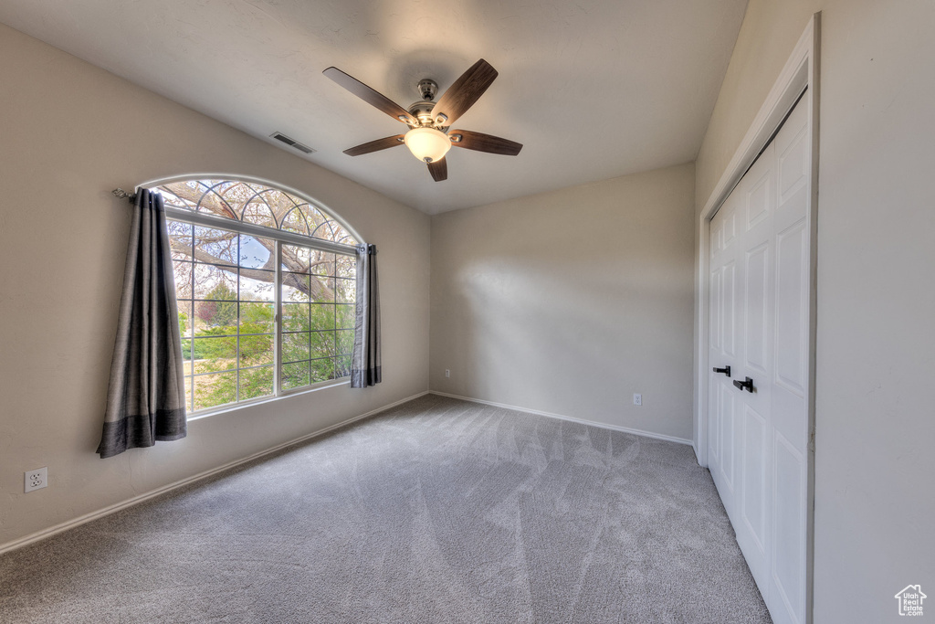 Empty room with a ceiling fan, baseboards, carpet, and visible vents