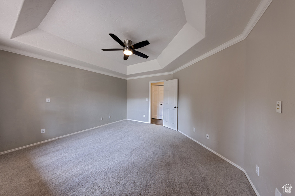 Unfurnished room with carpet, a tray ceiling, baseboards, and ceiling fan