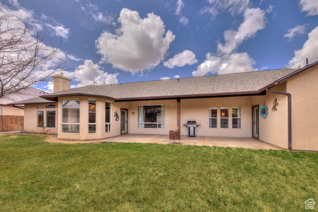 Rear view of property with a yard, stucco siding, a patio area, fence, and a chimney
