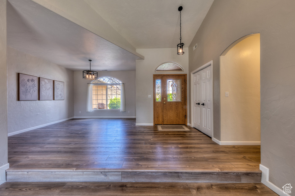 Entryway featuring baseboards, arched walkways, a notable chandelier, and wood finished floors